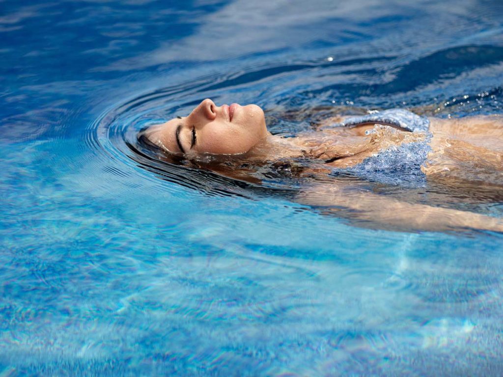 Woman Floating In The Pool.