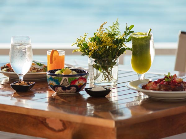 Mesa con comida y bebidas junto al mar.