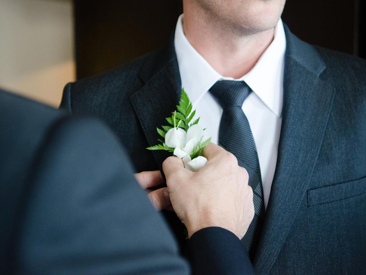 man getting flower attached to suits