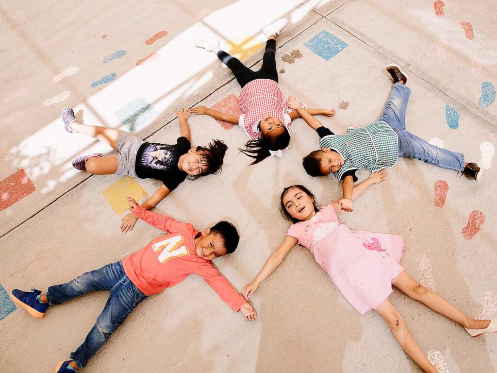 Niños tumbados en el suelo haciendo una estrella.