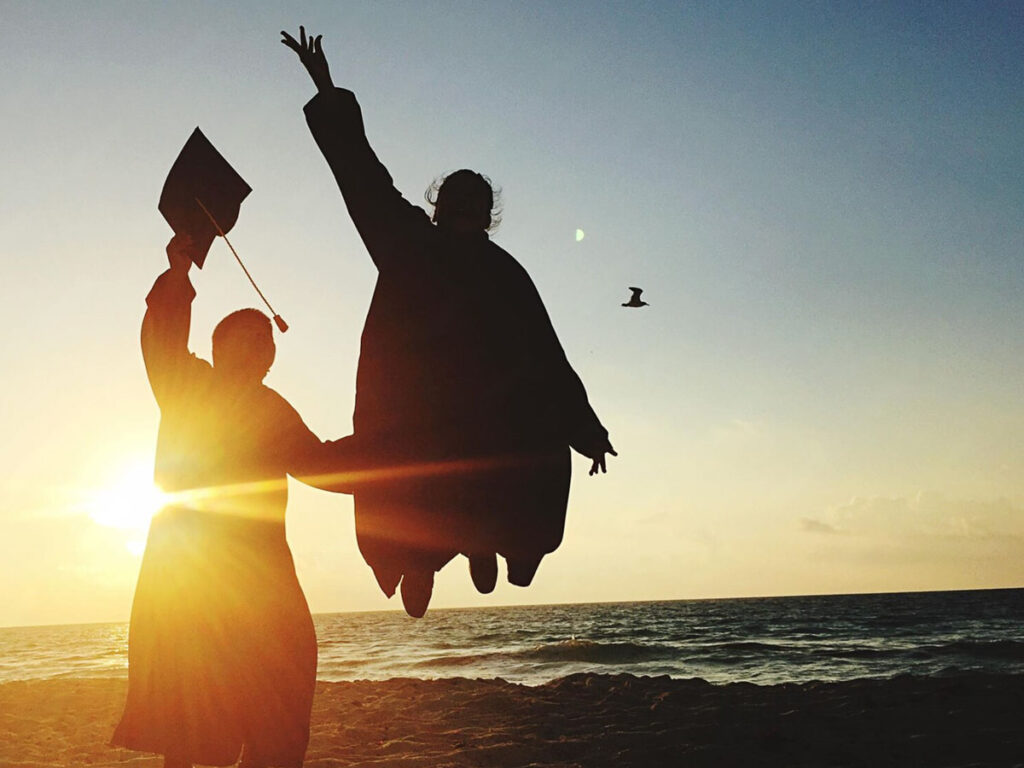 Graduates Throwing Caps On The Beach